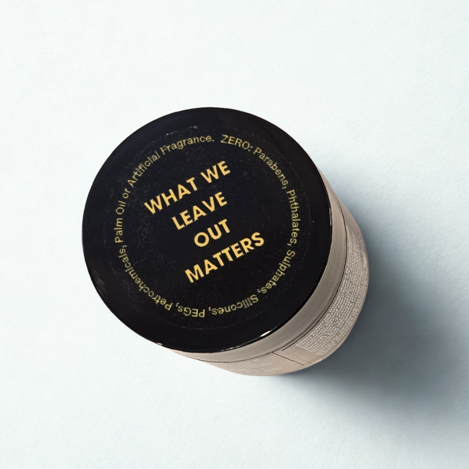 Cosmetics jar with black lid and amber glass jar on a light gray background. On the lid is written in yellow "What we leave out matters"